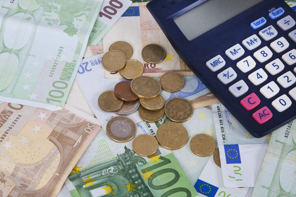 Euro-Geldscheine, Münzen und ein Taschenrechner symbolisieren die Kosten einer Bestattung.
