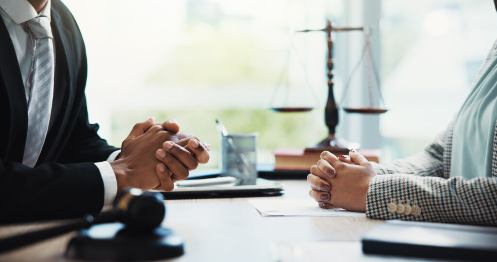 Anwalt berät Mandanten zur Nachlassverwaltung, im Vordergrund liegen Dokumente und eine Justizwaage.