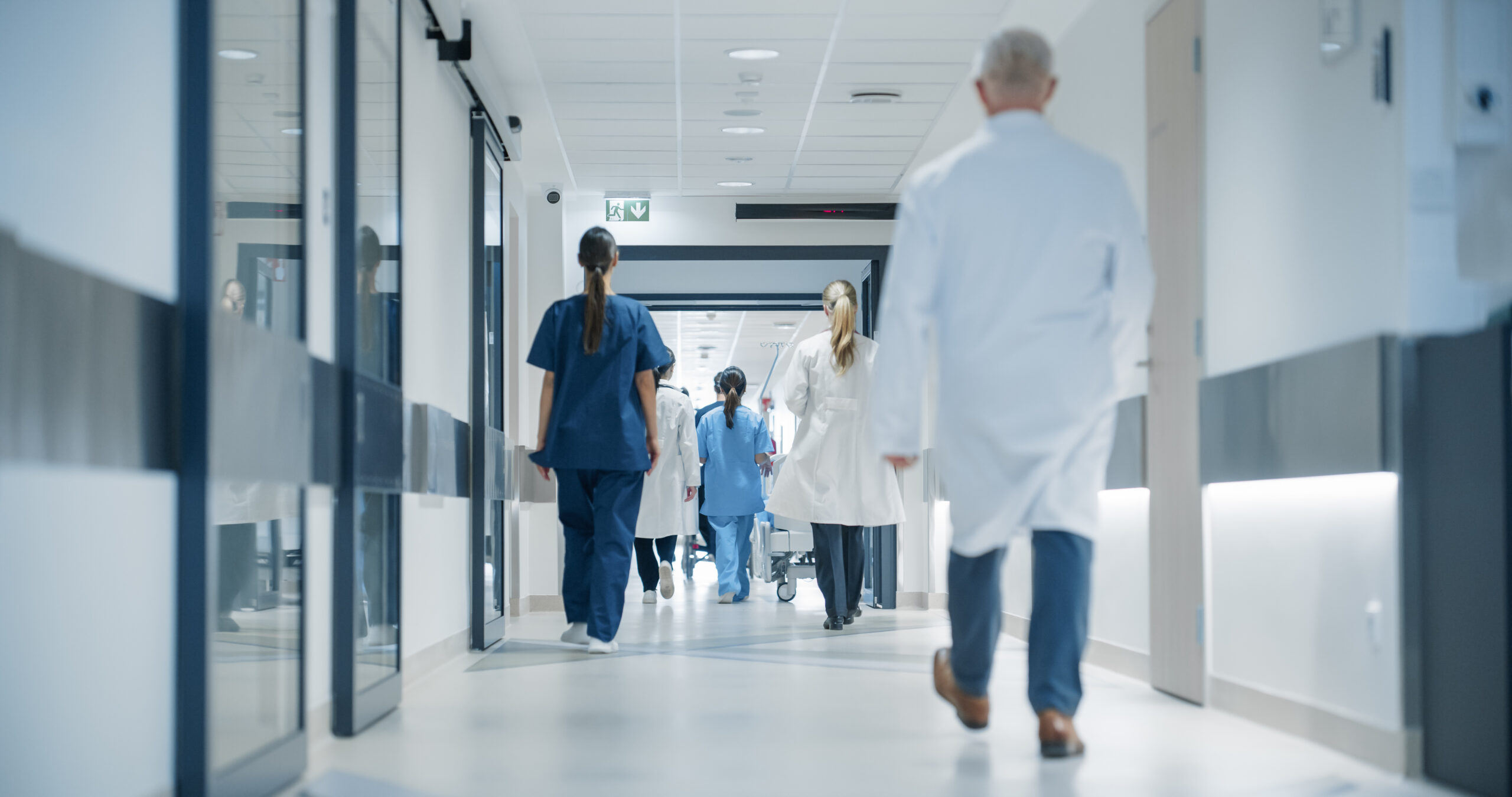 Ärzte und Pflegepersonal gehen durch den Krankenhausflur, symbolisch für einen Todesfall im Krankenhaus.