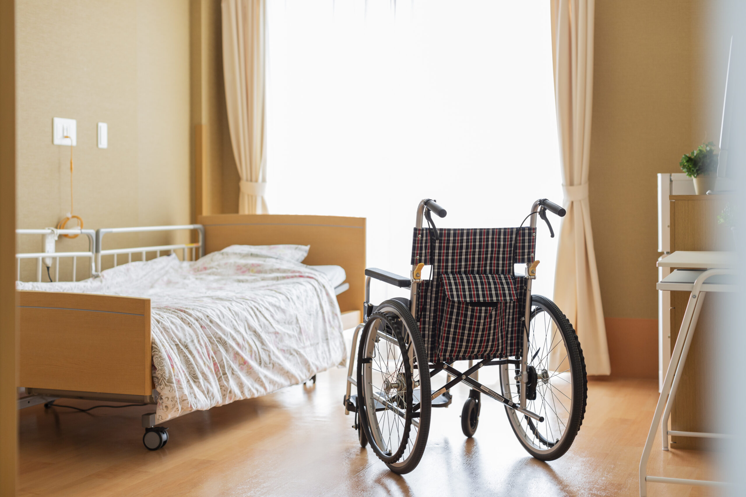 Leeres Pflegezimmer mit Bett und Rollstuhl nach einem Todesfall im Alten- oder Pflegeheim.