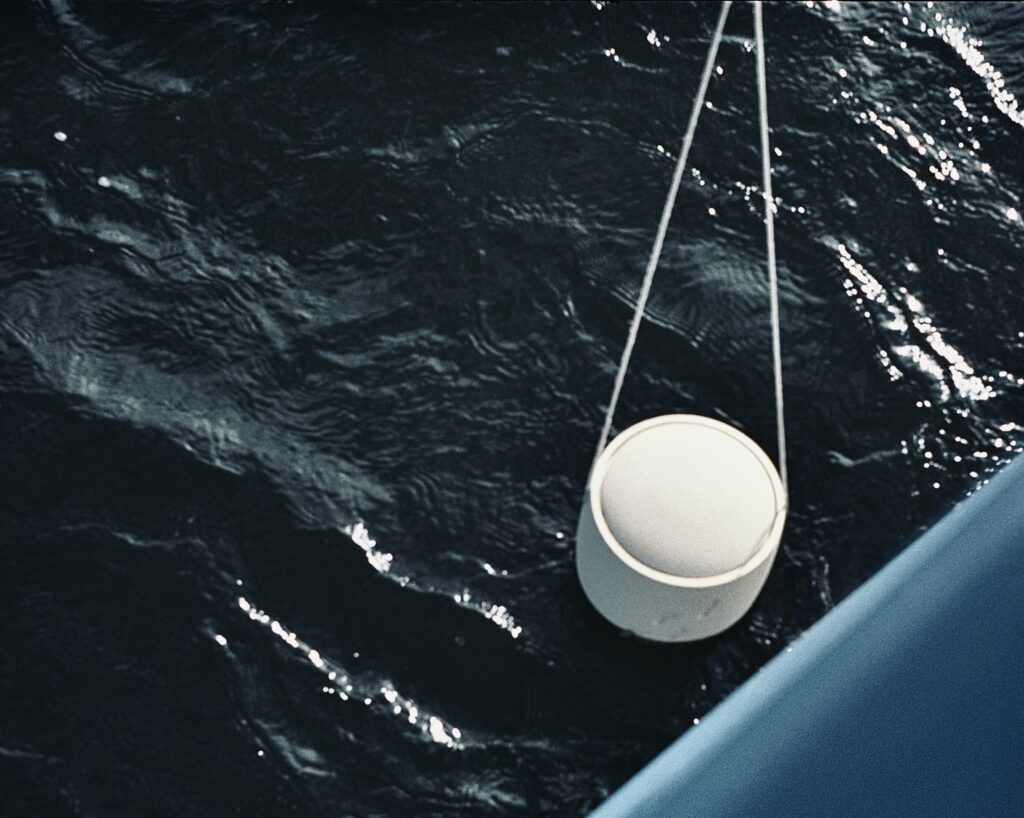 Eine Urne wird bei einer See-Bestattung vom Boot aus ins Meer hinabgelassen.